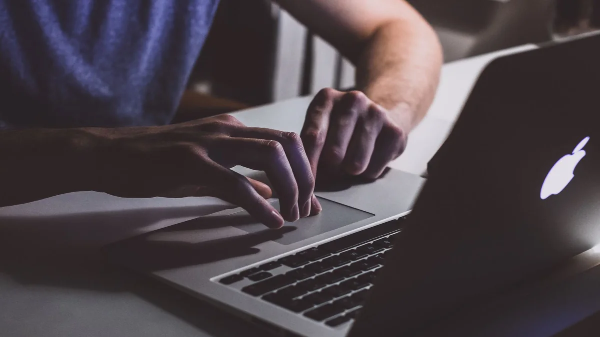 Mains sur le clavier d'un ordinateur portable dans une pièce sombre